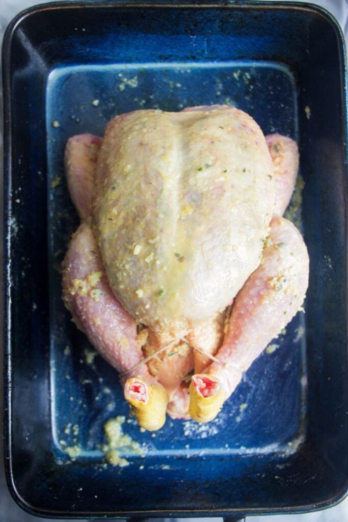 Herb roasted chciken ready to be roasted in a blue oven dish.