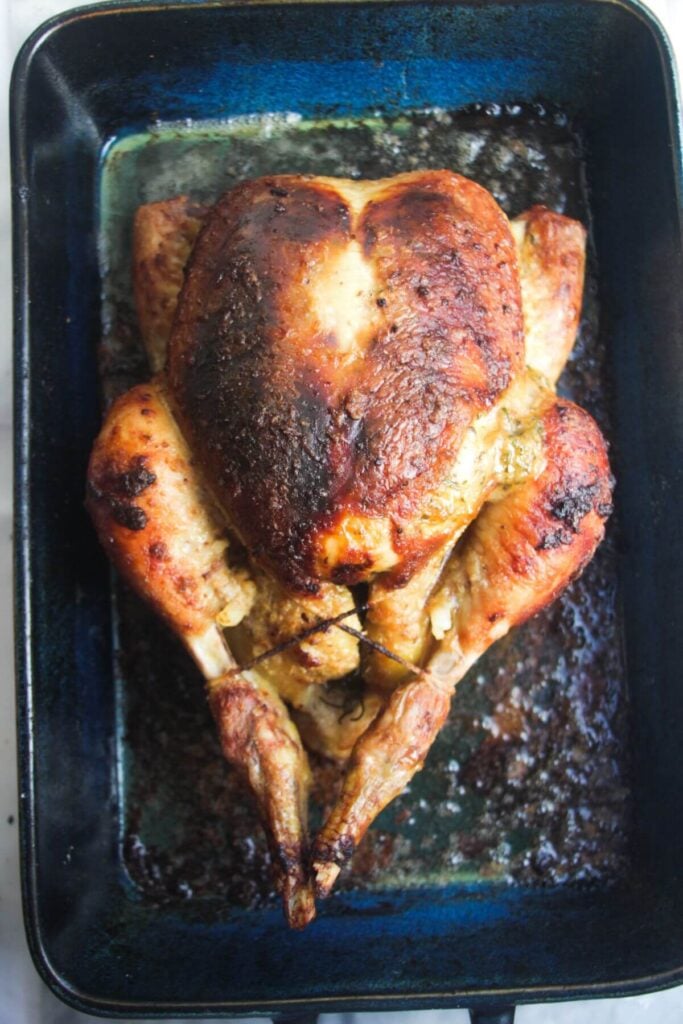Golden brown roasted chicken after cooking, in a blue oven dish.