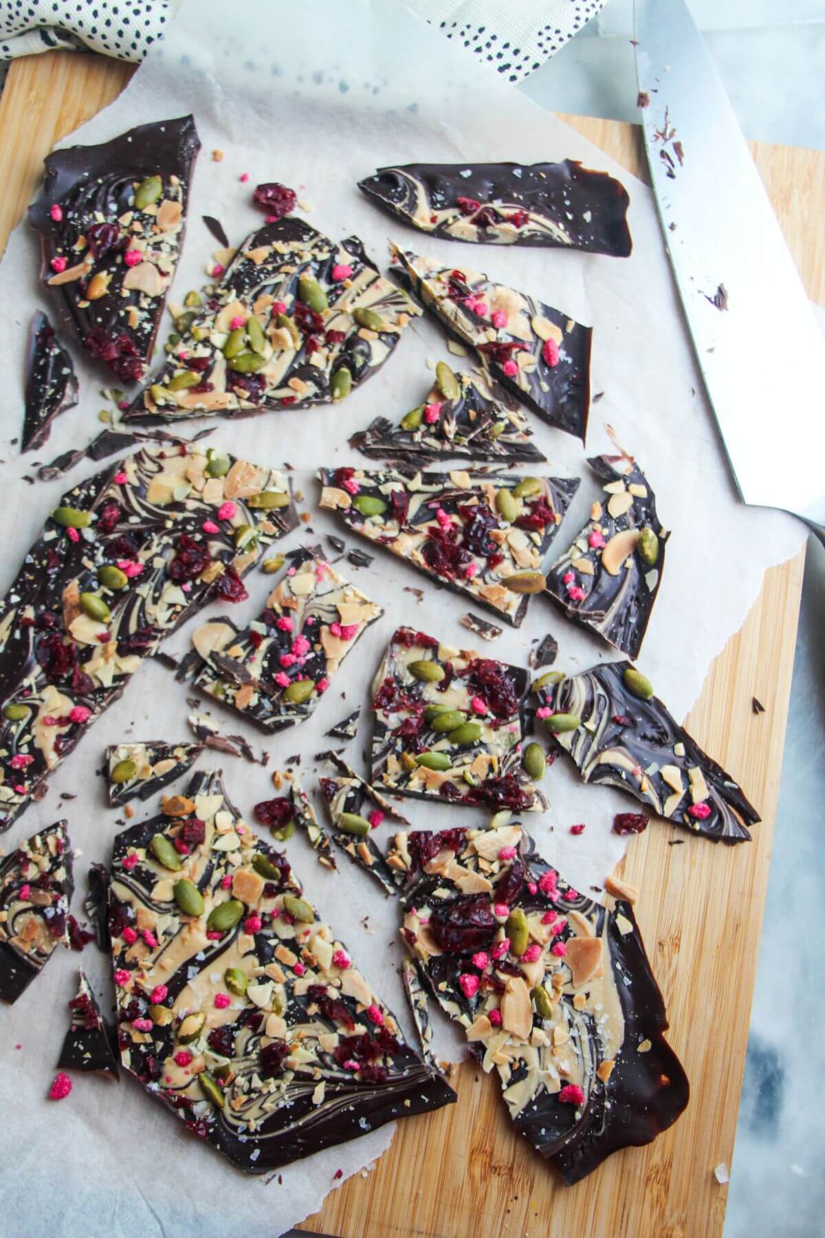 Chocolate almond bark broken into shards on a wooden board.