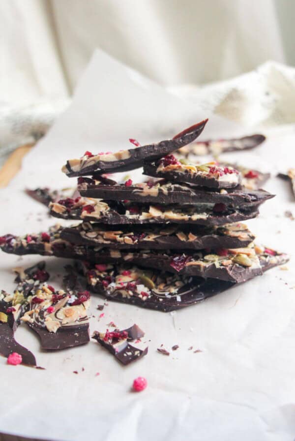 A pile of chocolate almond bark on a baking paper lined board.