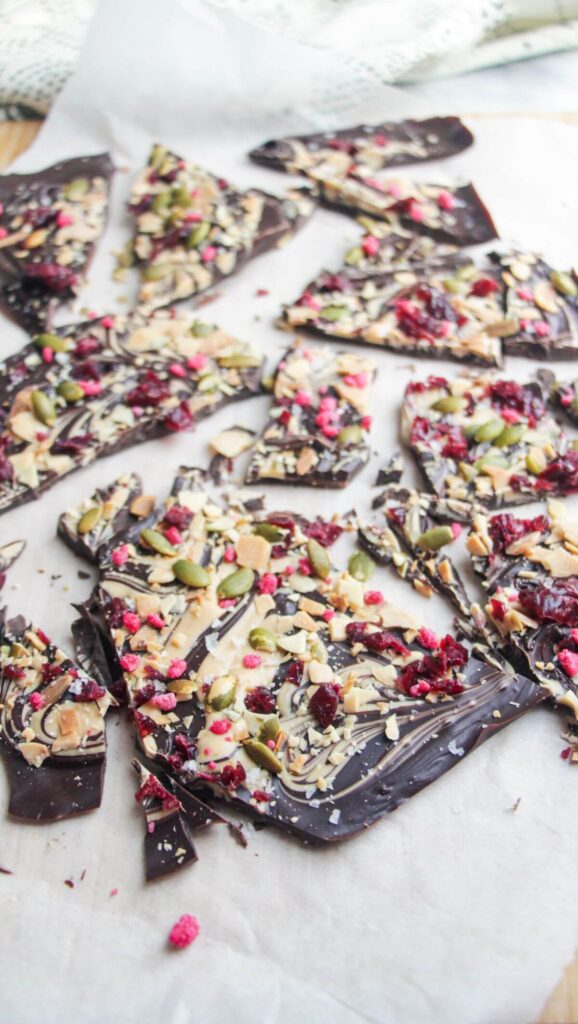 Chocolate almond bark broken into shards on a wooden board.