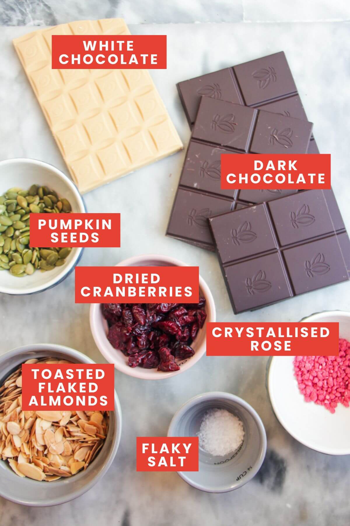 Chocolate almond bark ingredients laid out on a grey marble background and labelled.