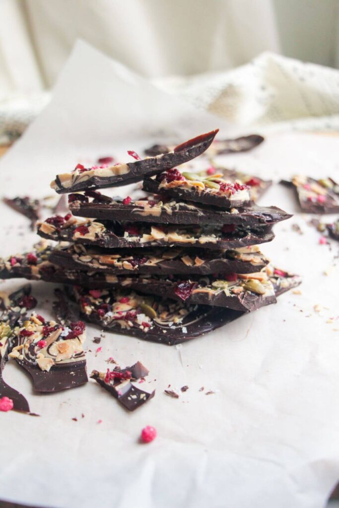 A pile of chocolate almond bark on a baking paper lined board.