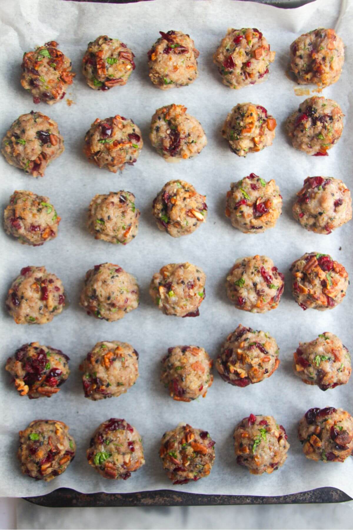 Cooked stuffing balls laid out on a baking paper lined tray.