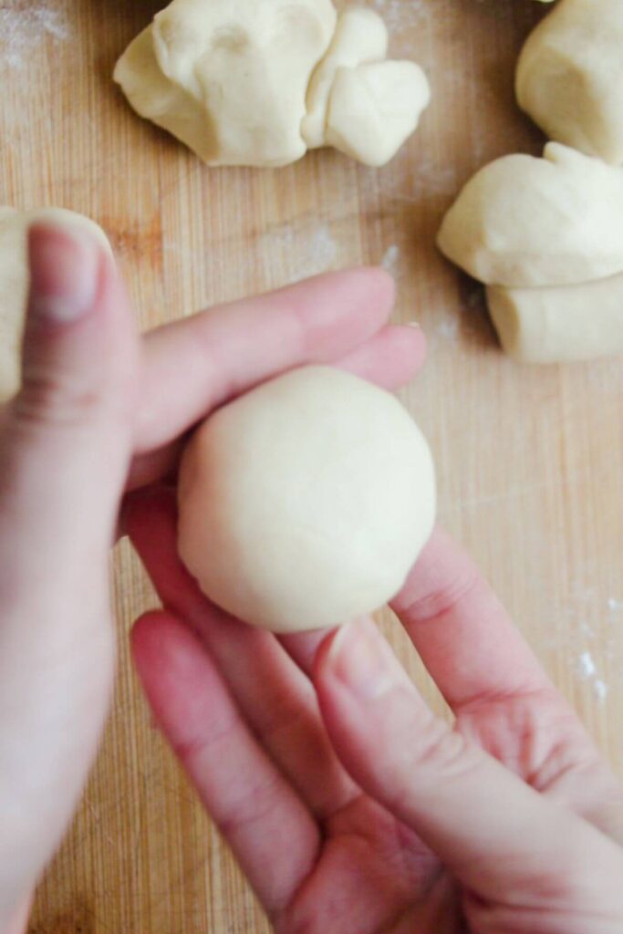 Hands holding up a small dough ball.