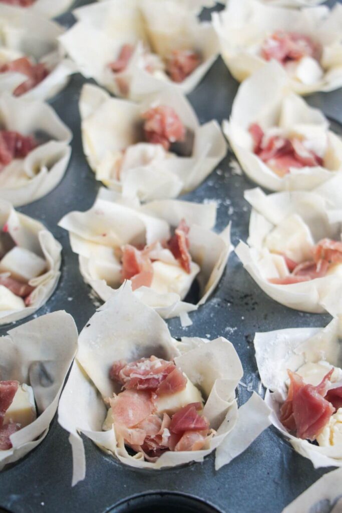 Brie, prosciutto and cranberry sauce in filo pastry cups.