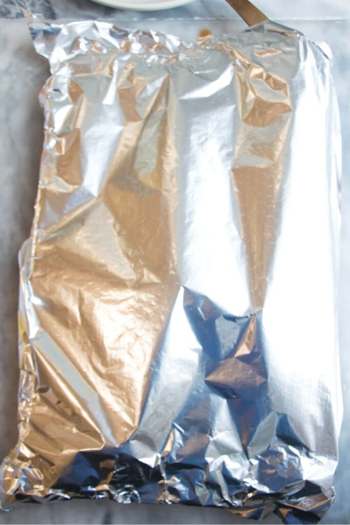 Foil covered oven tray with salmon fillet inside.