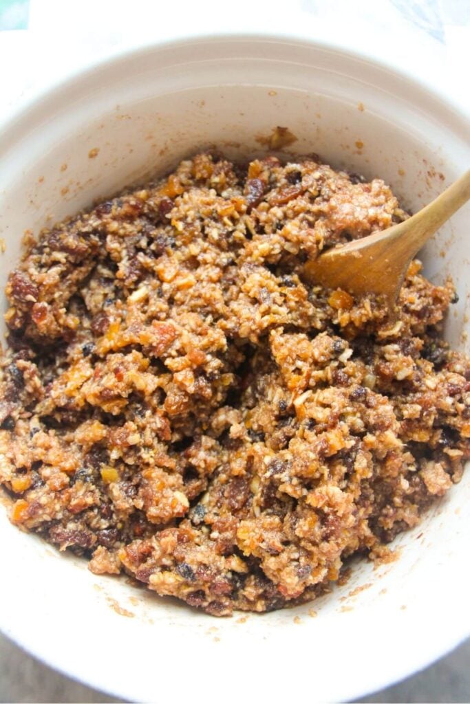 Christmas fruit mince in a large white bowl with a wooden spoon in the bowl.