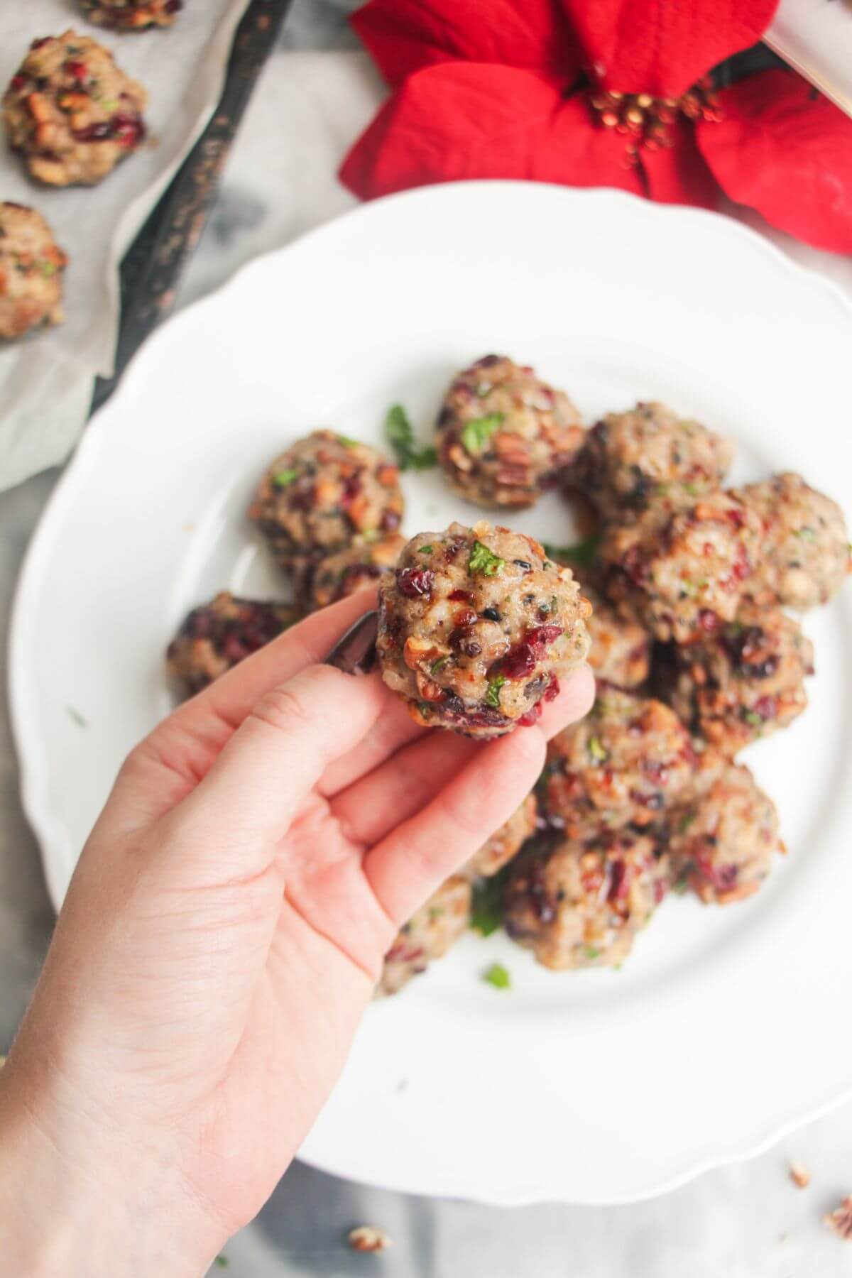 Hand holding stuffing ball with plate of stuffing balls in the background.