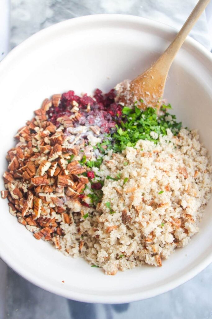 Stuffing ball ingredients in a large white mixing bowl with a wooden spoon.