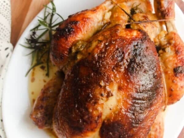 Juicy herb roasted chicken on a white oval plate.