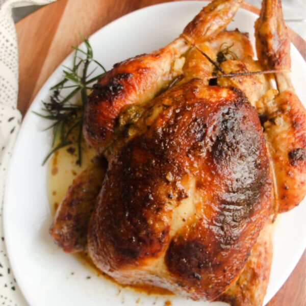 Juicy herb roasted chicken on a white oval plate.