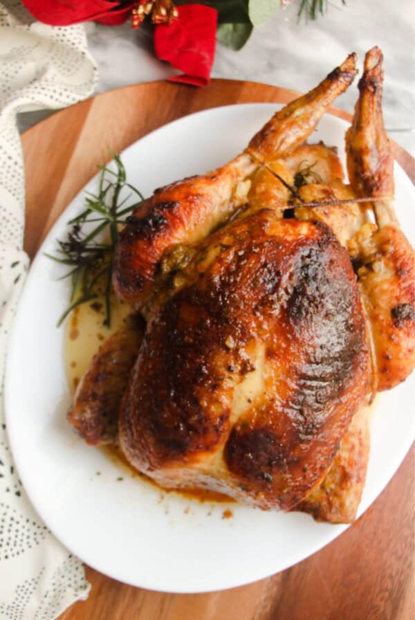 Juicy herb roasted chicken on a white oval plate.
