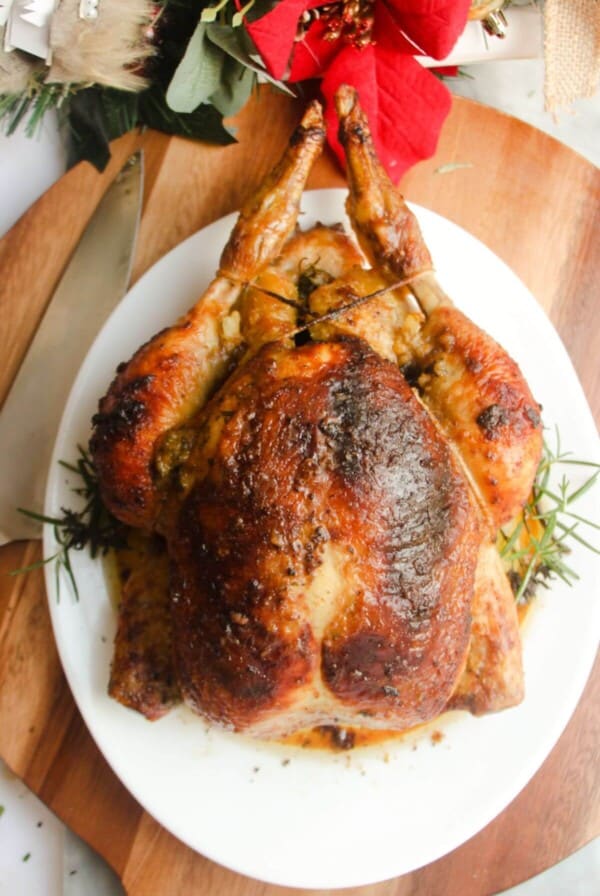 Juicy herb roasted chicken on a white oval plate.