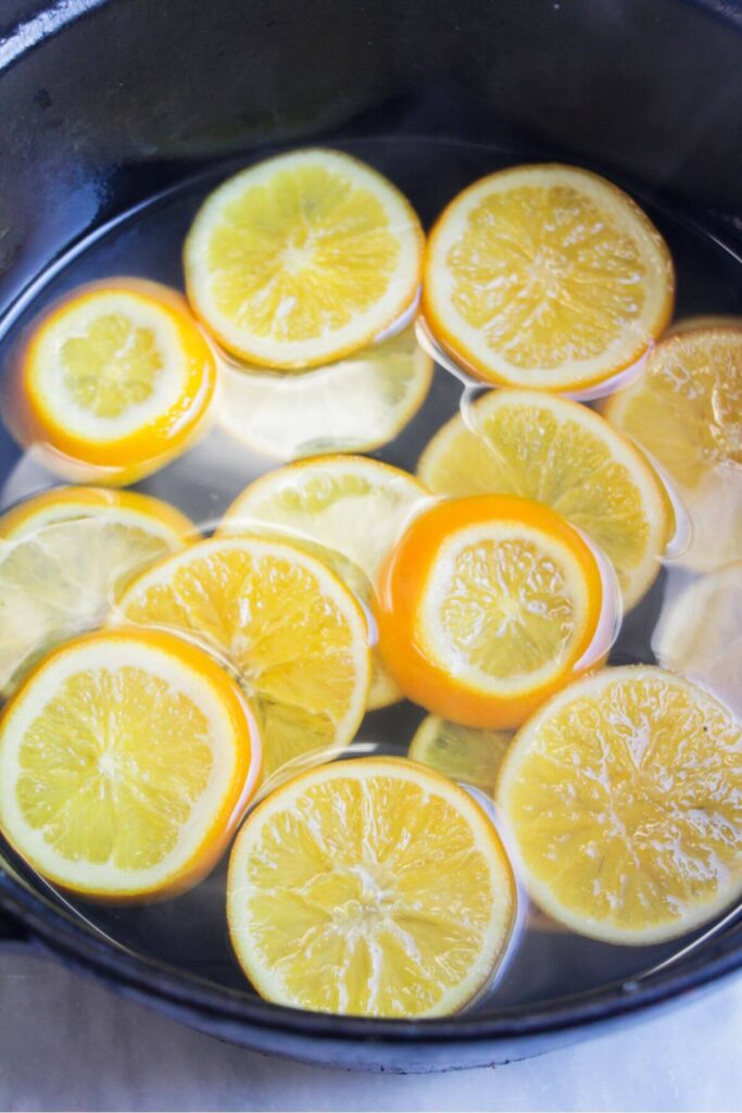 Orange slices in a large pot simmering in sugar syrup.