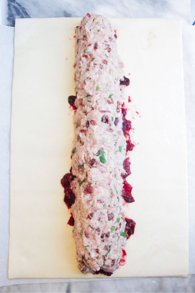 Sausage meat laid out in a long log along a sheet of puff pastry.