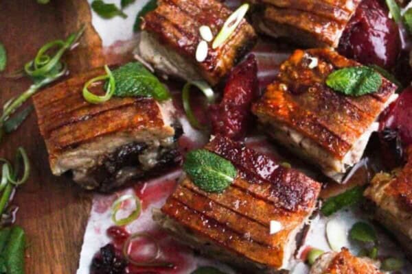 Square pieces of slow roasted pork belly on a wooden serving platter.