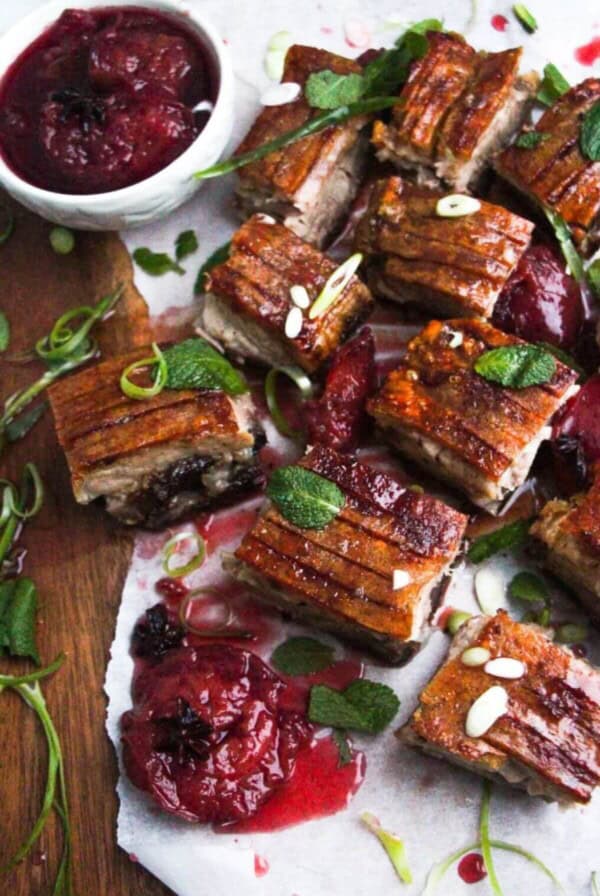 Square pieces of slow roasted pork belly on a wooden serving platter.