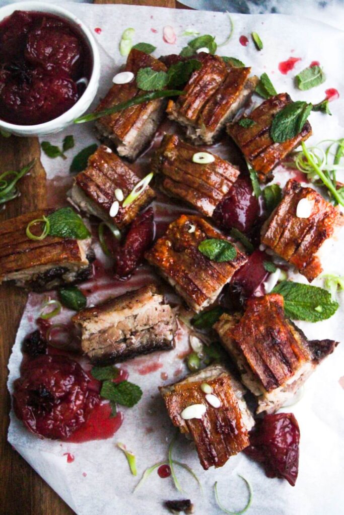 Square pieces of slow roasted pork belly on a wooden serving platter.