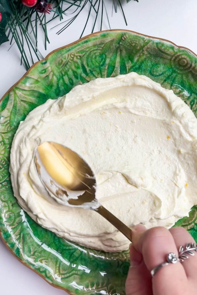Smoothing whipped feta onto a small green plate.