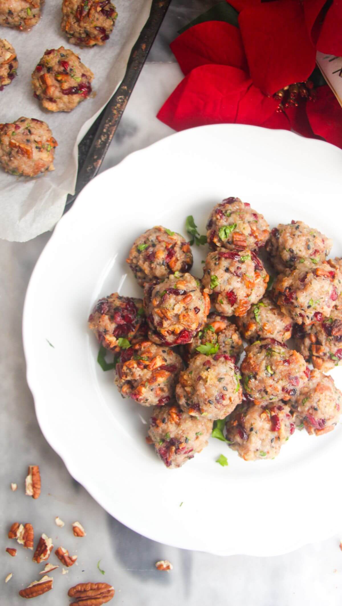 Cranberry pecan stuffing balls piled on a large white plate with more stuffing balls in the background.