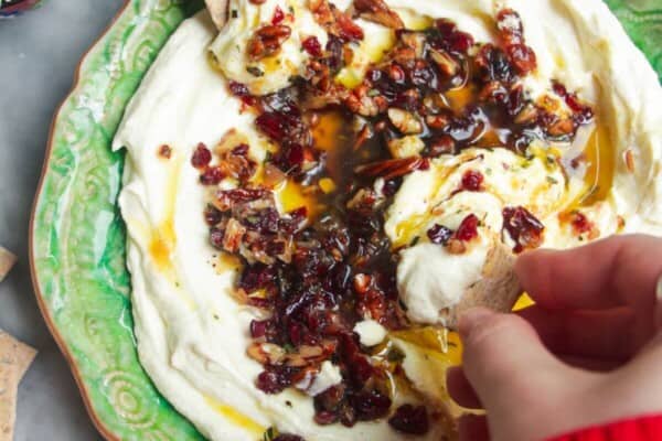 Whipped feta dip on a small green plate, topped with oil and nuts.