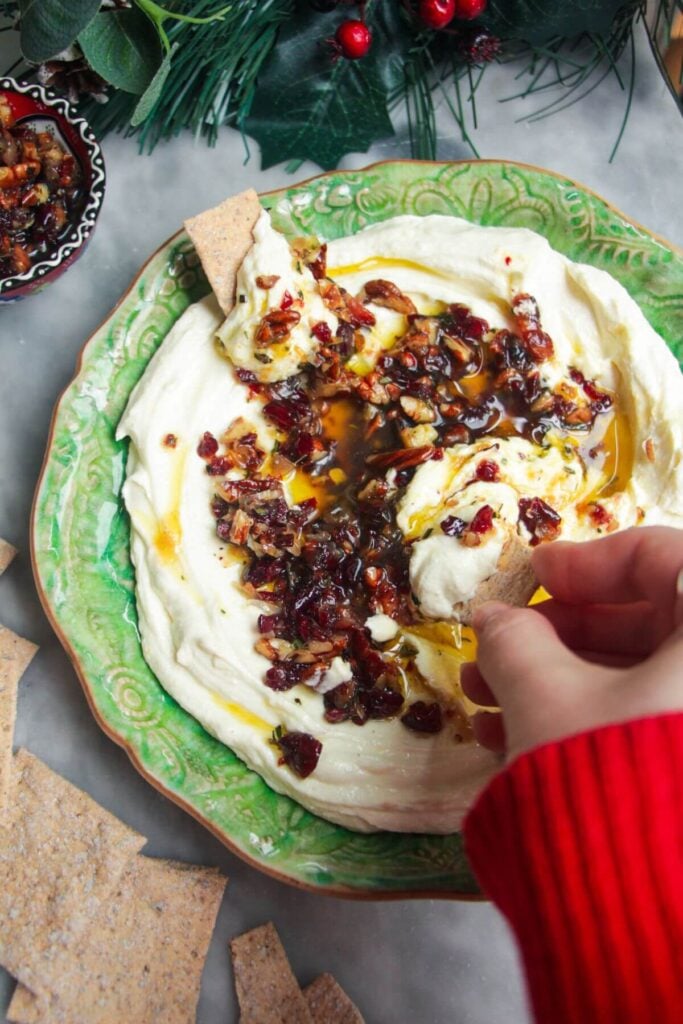 Whipped feta dip on a small green plate, topped with oil and nuts.