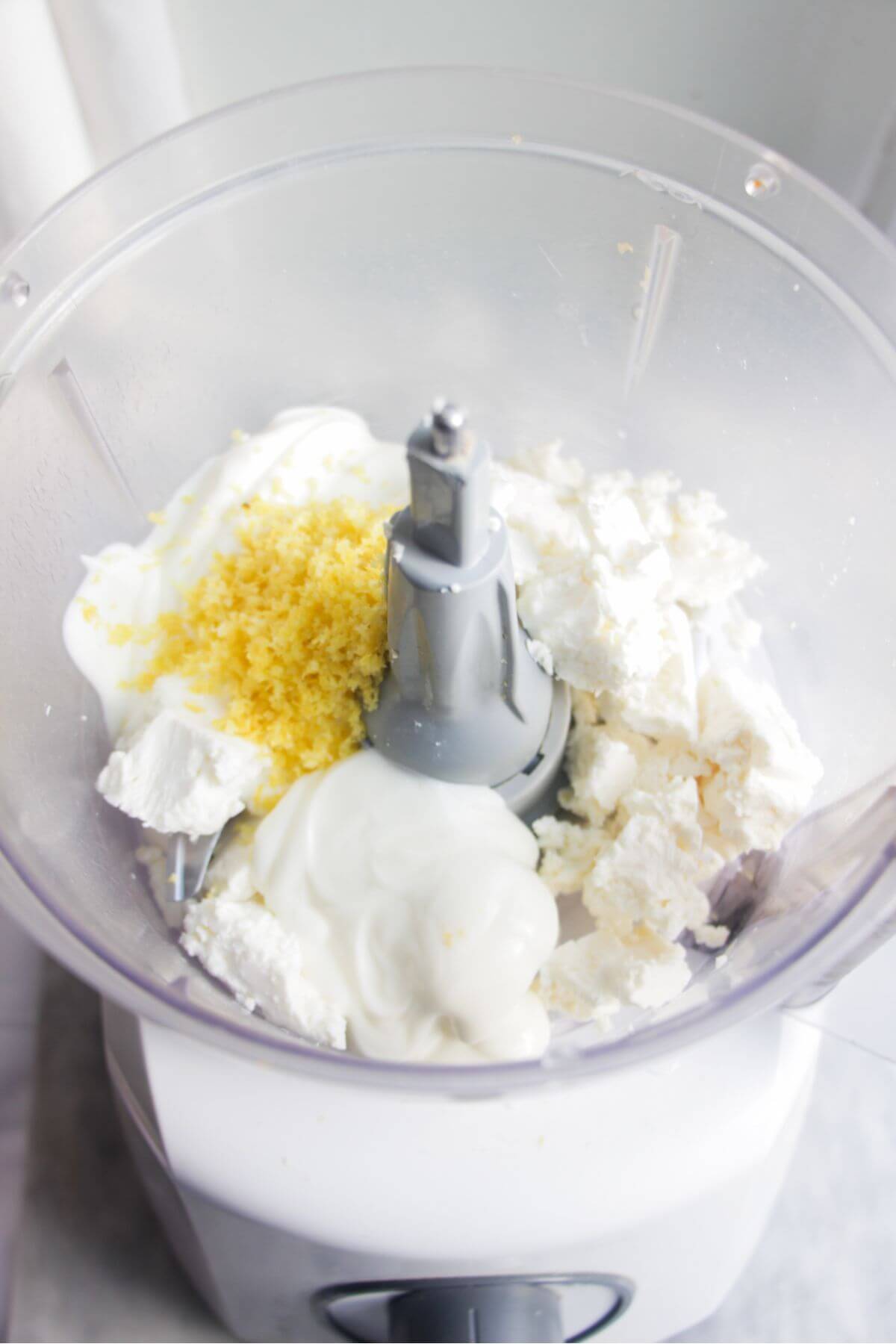 Ingredients for whipped feta in the bowl of a food processor.