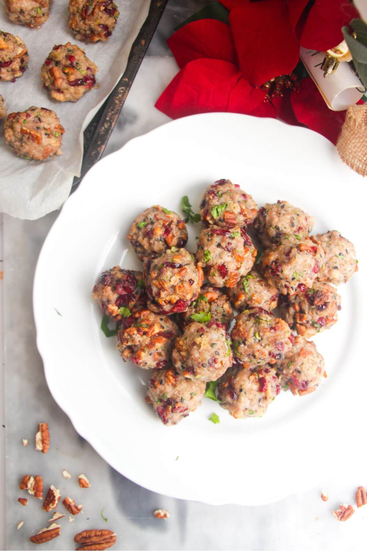 Cranberry pecan stuffing balls piled on a large white plate with more stuffing balls in the background.