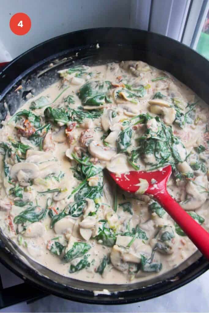 Stirring creamy mushroom sauce in a large pan.