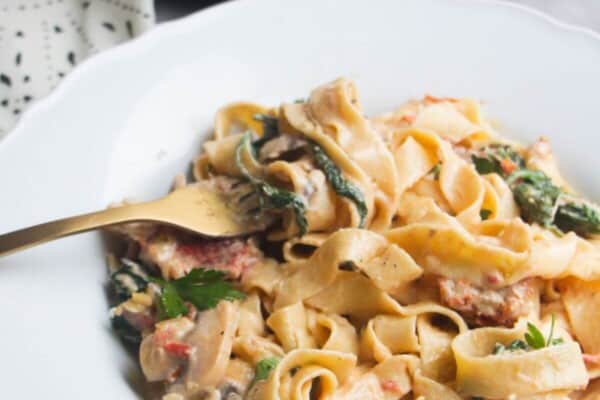 Close up of a bowl of creamy mushroom pasta, with a fork in it.
