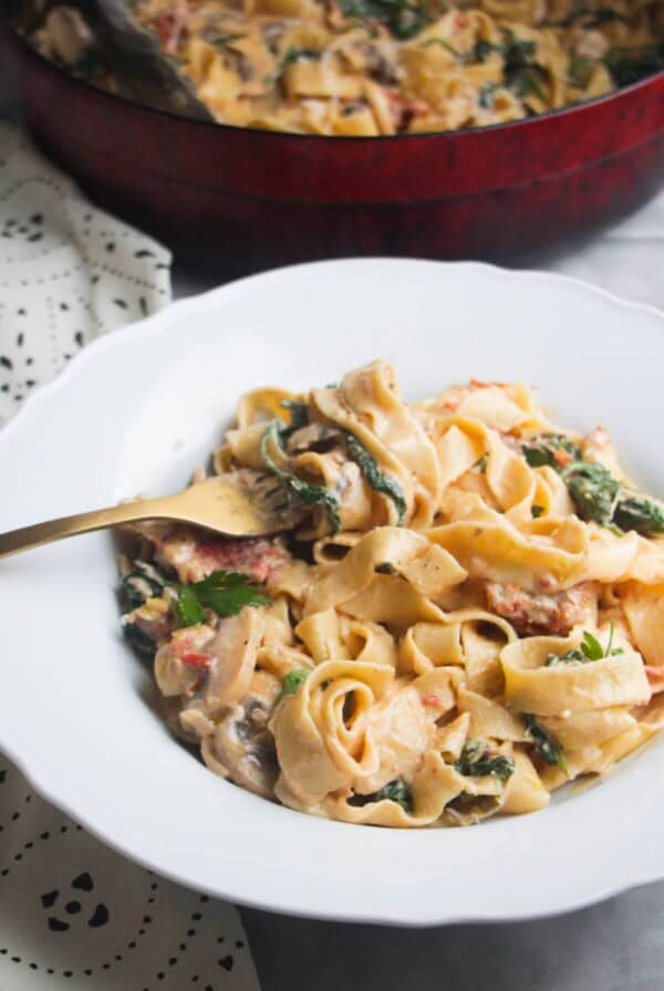 Close up of a bowl of creamy mushroom pasta, with a fork in it.