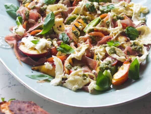 Grilled peach, burrata, tomato salad on a large blue serving platter.