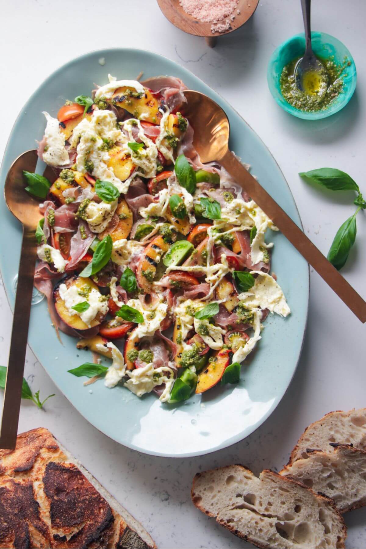Grilled peach, burrata, tomato salad on a large blue serving platter.