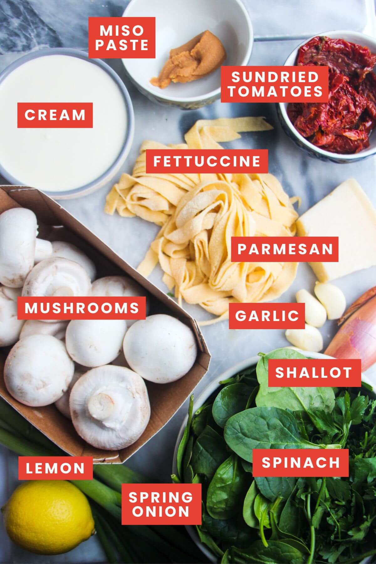 Ingredients for creamy mushroom fettuccine alfredo on a grey marble background and labelled.