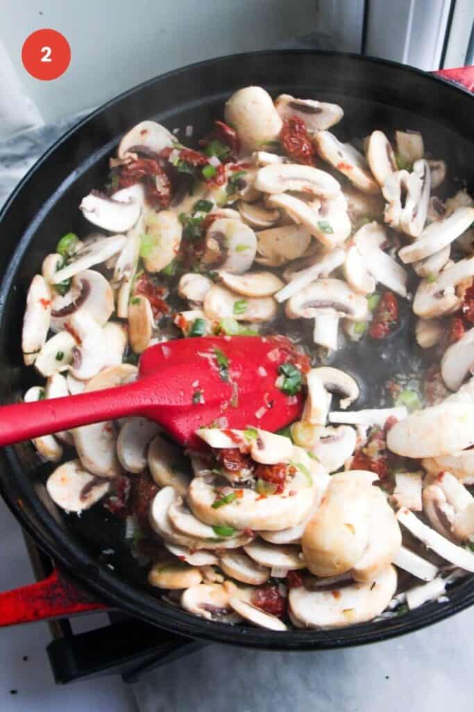 Sliced mushrooms stirred in a large pan.