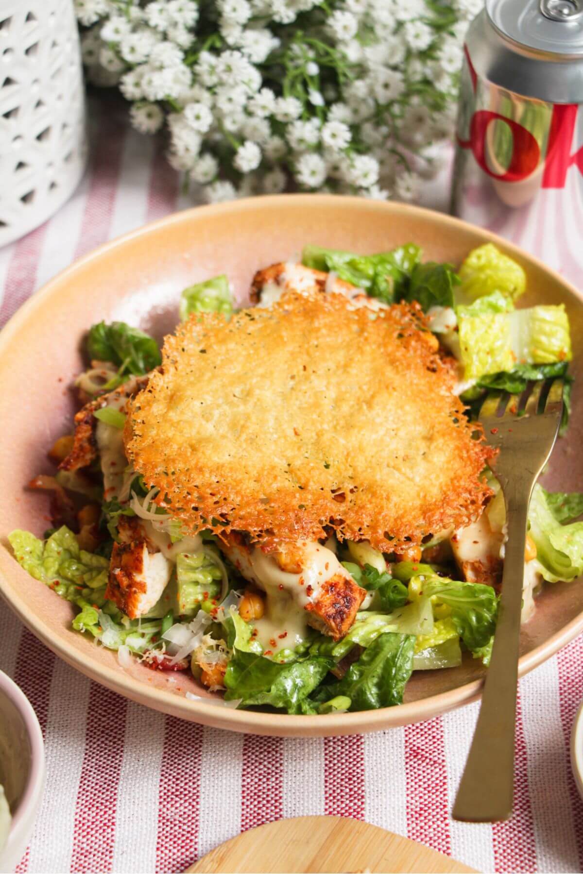 Parmesan crisp on top of caesar salad in a pink bowl.