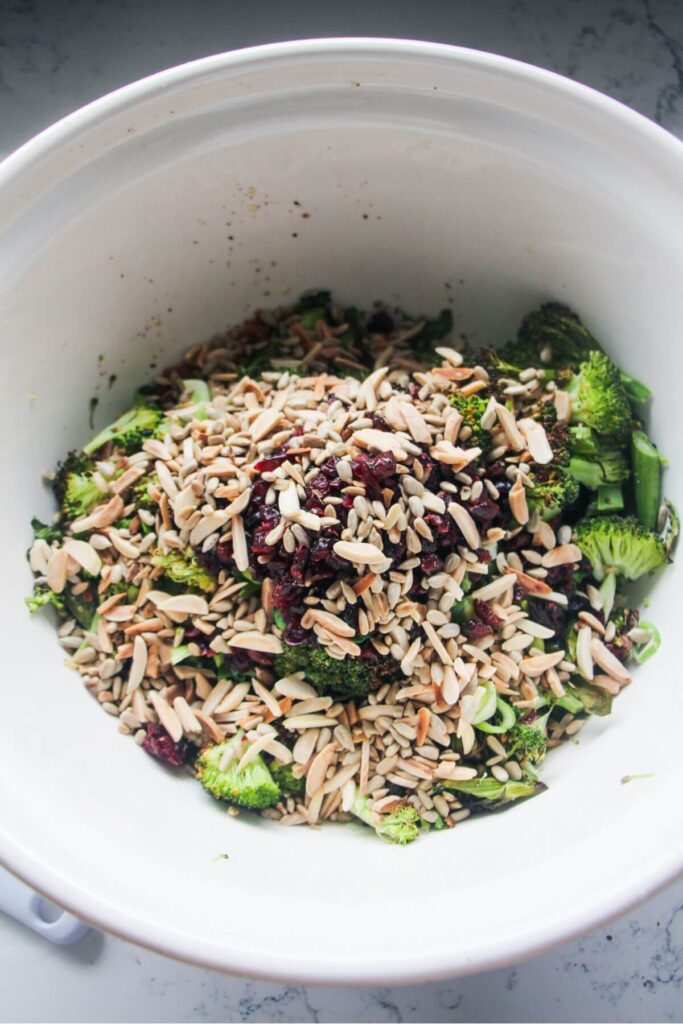Almonds and sunflower seeds added to a large bowl with grilled broccoli.