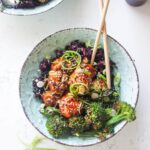 Glazed Asian chicken meatballs with rice and broccoli in a small blue bowl.