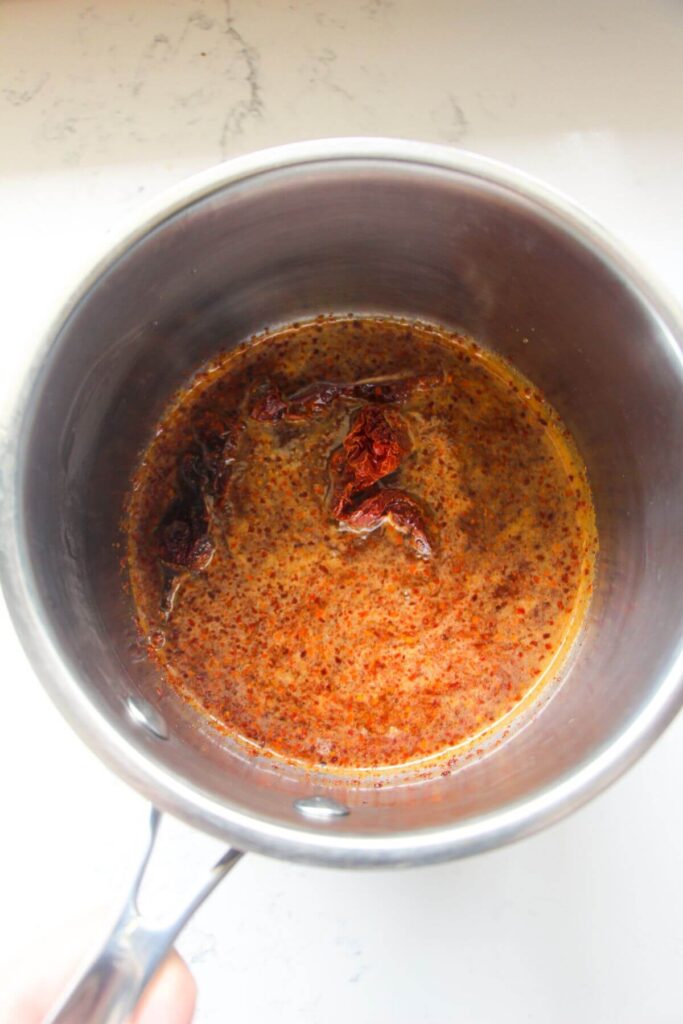 Honey and chilli flakes bubbling up in a small silver pot.