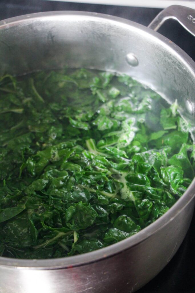Silverbeet leaves in a large pot of boiling water.