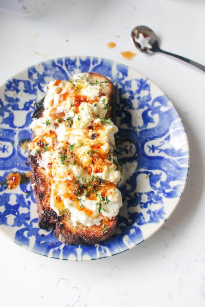Burrata on a piece of toasted sourdough with hot honey and thyme on top.