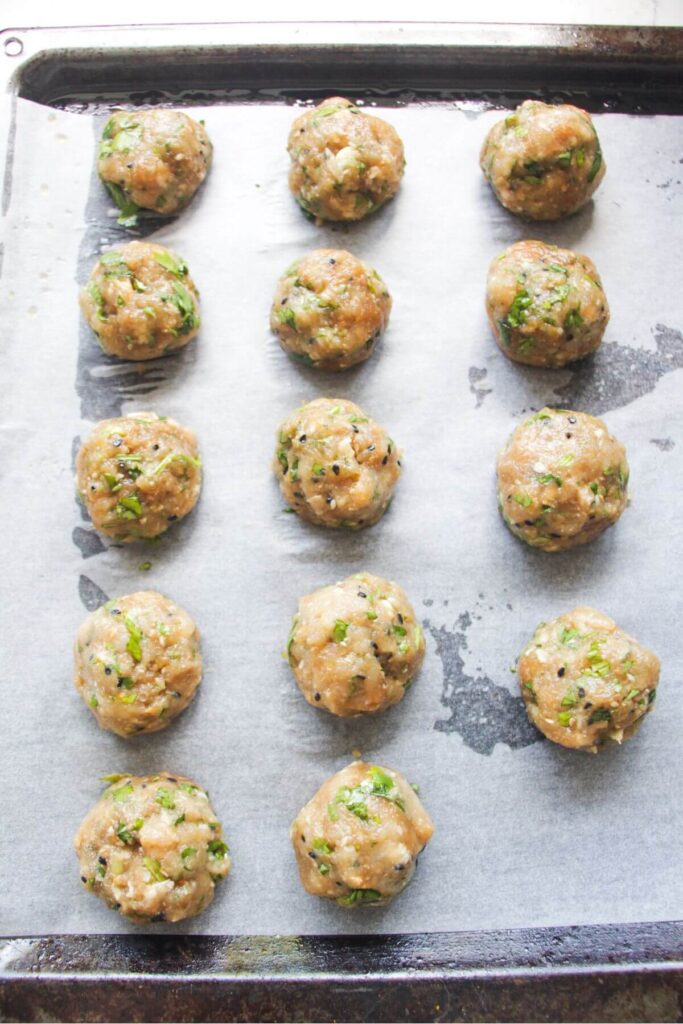 Chicken meatballs on a lined oven tray.