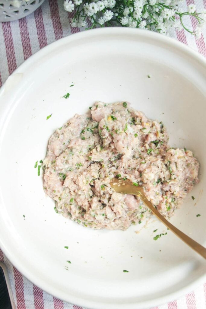 Greek chicken meatball mixture combined in a large mixing bowl.