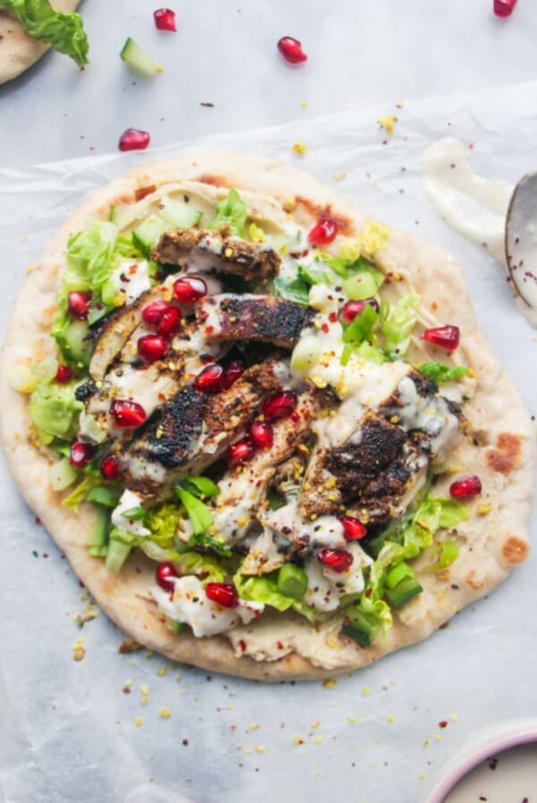 Chicken shawarma wrap on a grey marble background with a small bowl of tahini sauce on the side.