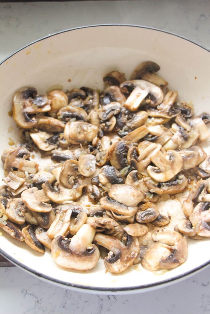 Mushrooms cooked in a white skillet.