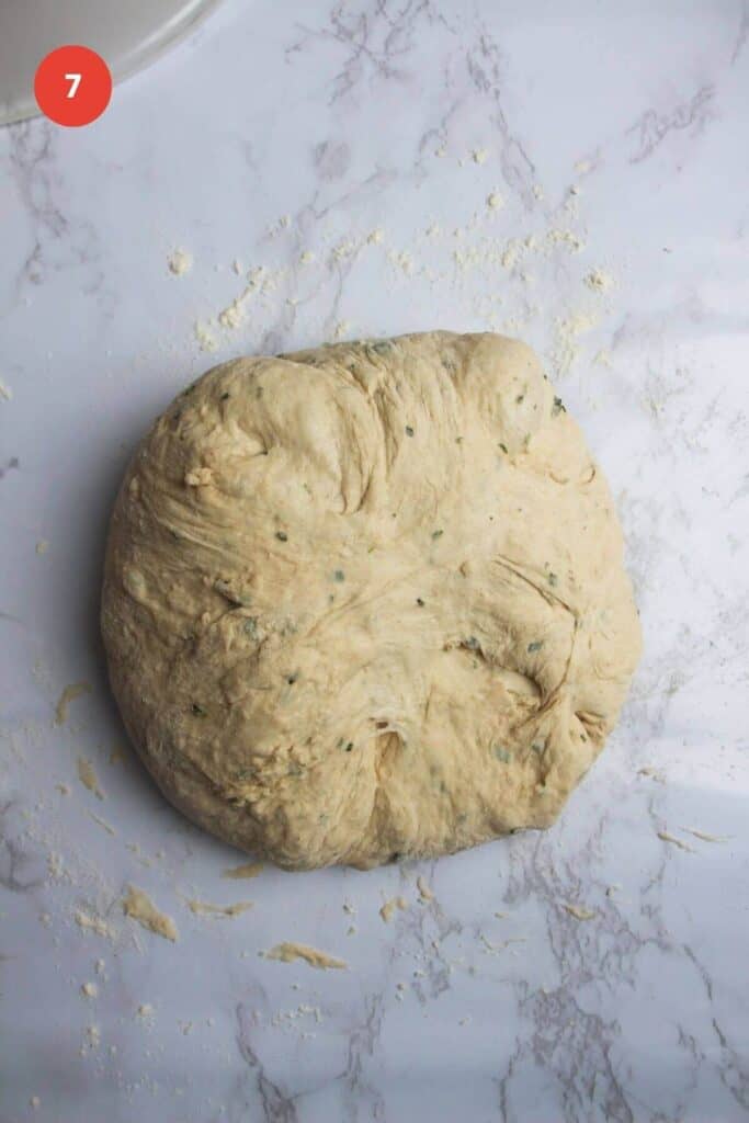 Rosemary parmesan bread dough shaped on parchment paper.