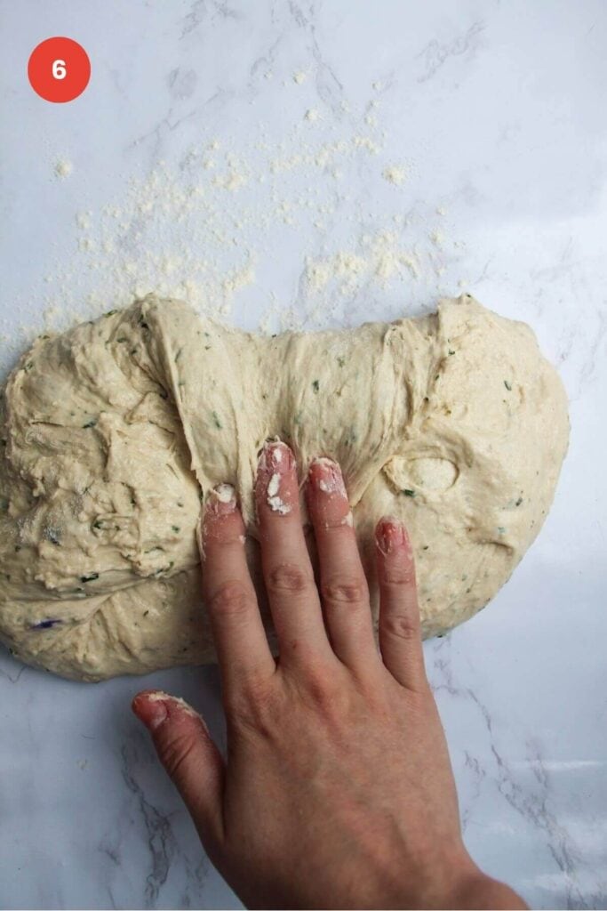 Hand folding bread dough over itself.