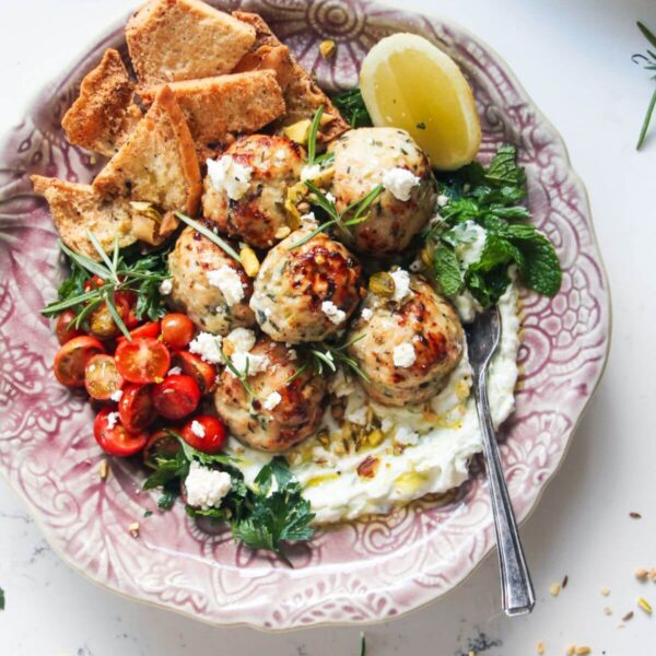 Fresh, zesty, juicy Greek chicken meatballs are a super easy, versatile 20 minute meal. Piled onto quick tzatziki sauce, topped with creamy feta, cherry tomatoes and herbs, they make a wonderful weeknight winner the whole family will love.