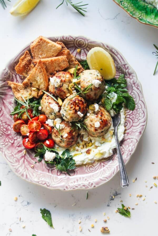 Fresh, zesty, juicy Greek chicken meatballs are a super easy, versatile 20 minute meal. Piled onto quick tzatziki sauce, topped with creamy feta, cherry tomatoes and herbs, they make a wonderful weeknight winner the whole family will love.